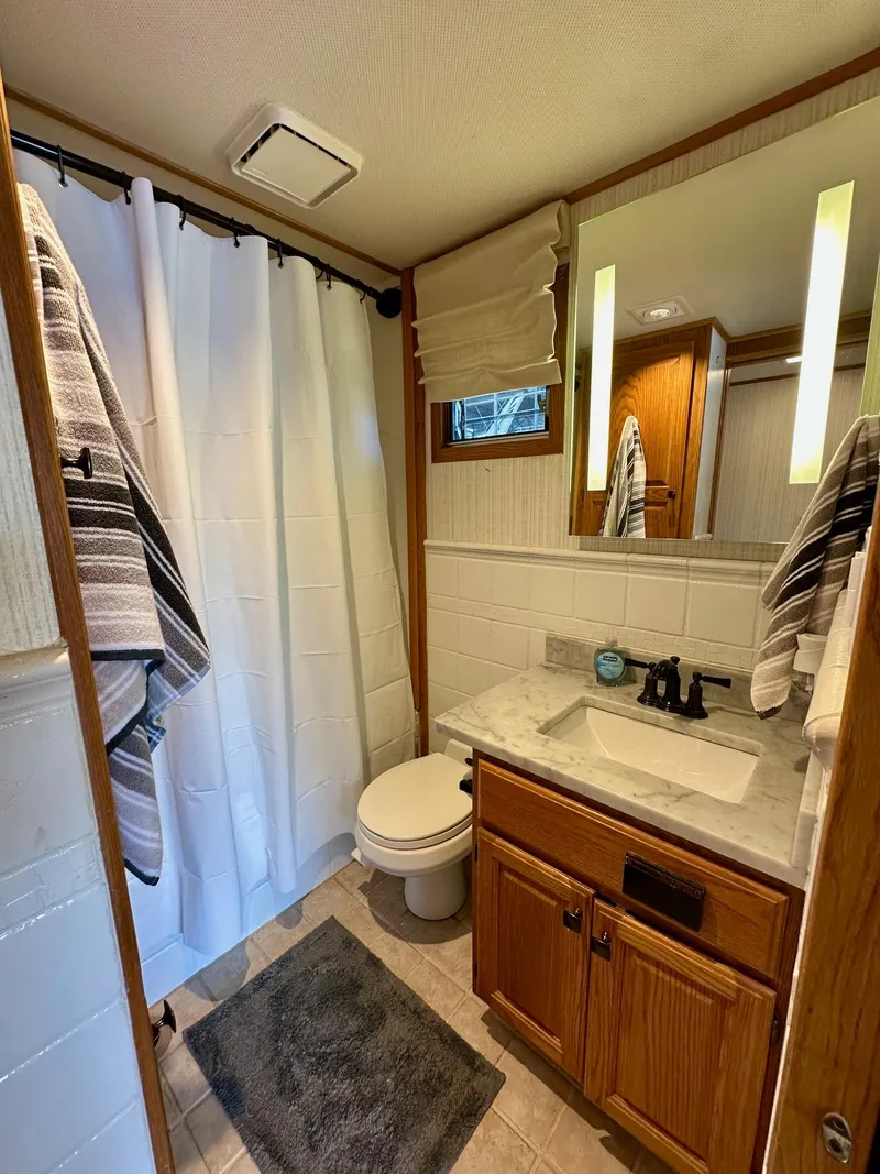 Slide: The Image of Compact bathroom in 1995 Lazy Days 16x75 houseboat with shower, sink, and wooden cabinetry. - 12