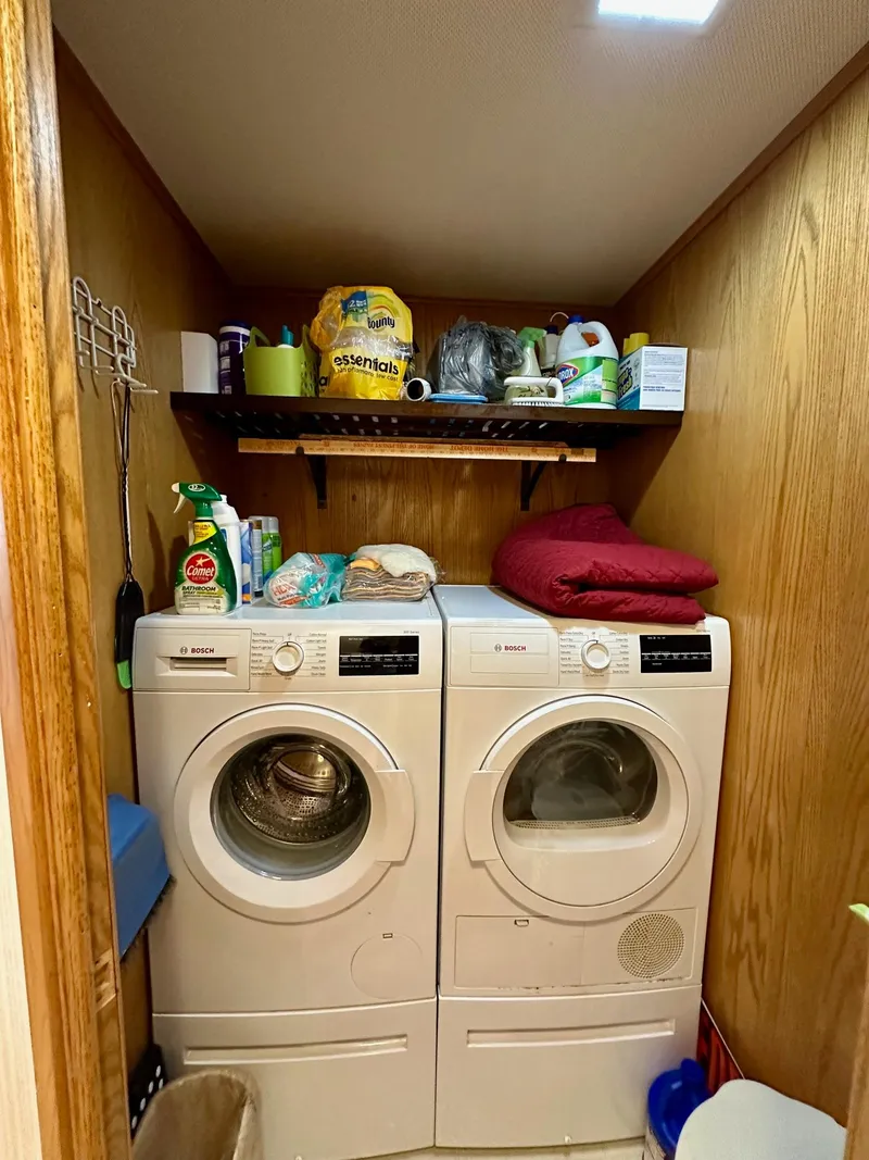 Slide: The Image of Laundry room with washer, dryer, and storage shelf in a 1995 Lazy Days 16x75 model. - 14