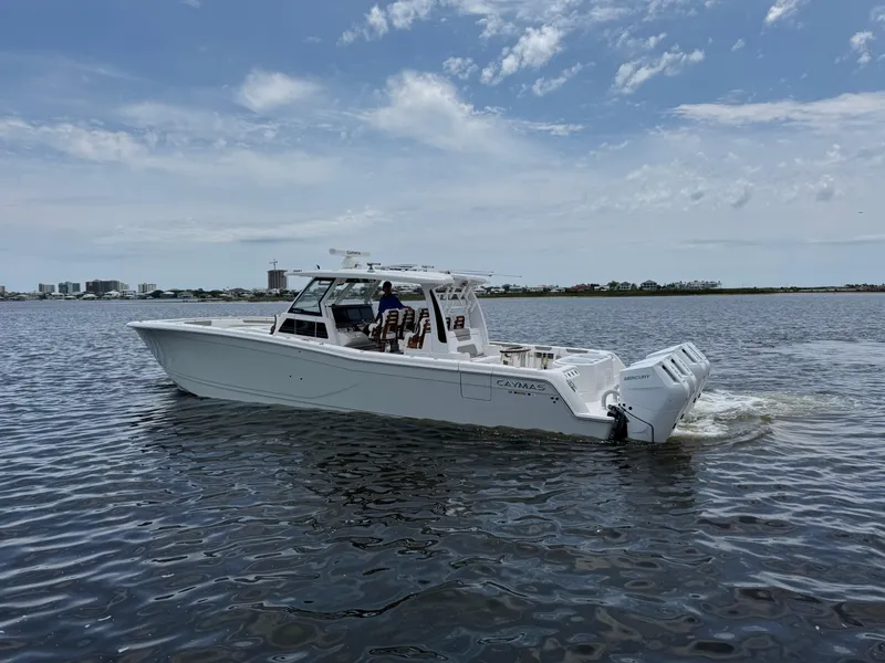 Slide: The Image of 2026 Caymas 44 CT boat cruising on a calm waterway under a partly cloudy sky. - 13