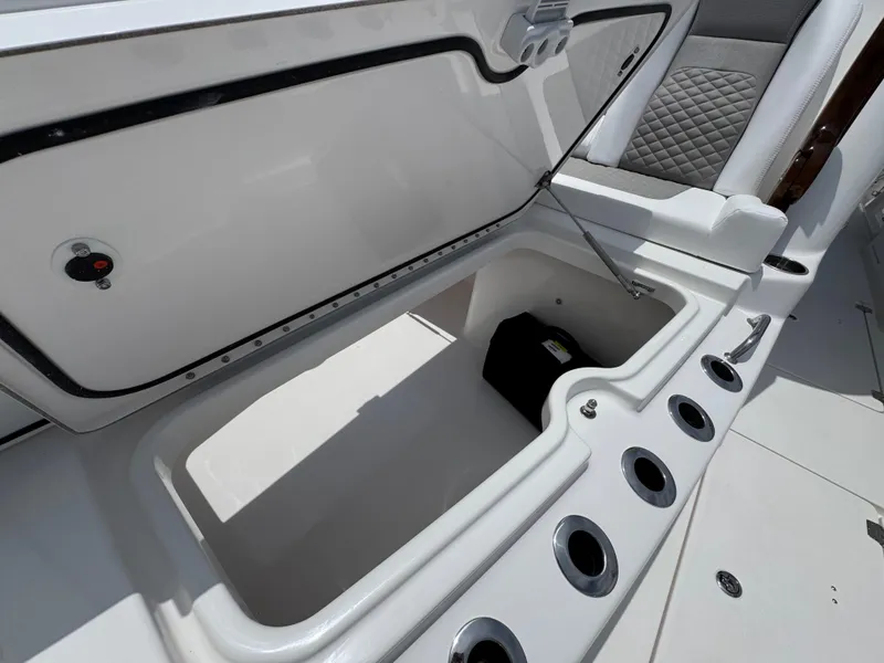 Slide: The Image of Open storage compartment on 2026 Caymas 44 CT boat with rod holders and quilted seating. - 25