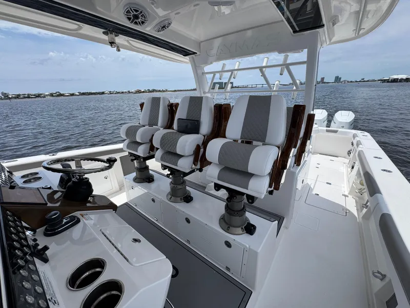 Slide: The Image of 2026 Caymas 44 CT boat interior with modern seating and steering, overlooking calm waters. - 33