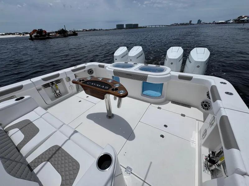Slide: The Image of 2026 Caymas 44 CT boat deck with seating, table, and outboard motors on a sunny day. - 44