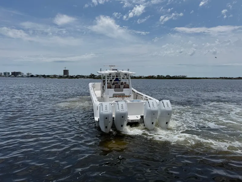 Slide: The Image of 2026 Caymas 44 CT boat with multiple engines cruising on open water under a cloudy sky. - 6