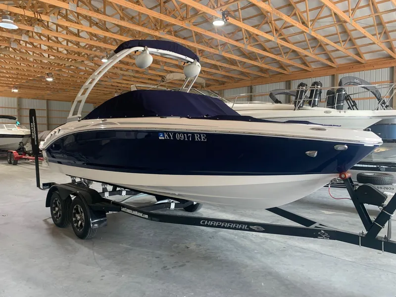 The Image of 2020 Chaparral 21 Surf boat in storage, blue and white, on a trailer. - 0