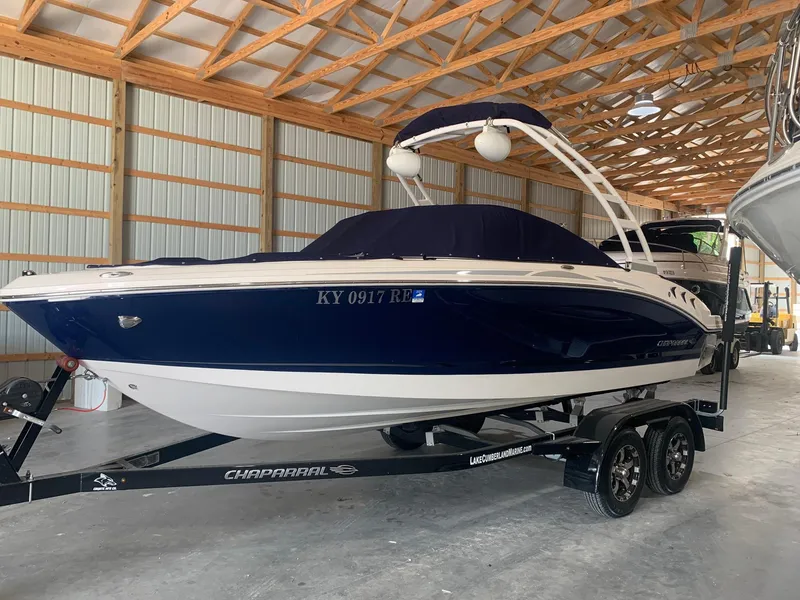 Slide: The Image of 2020 Chaparral 21 Surf boat in storage, blue and white, on a trailer. - 1