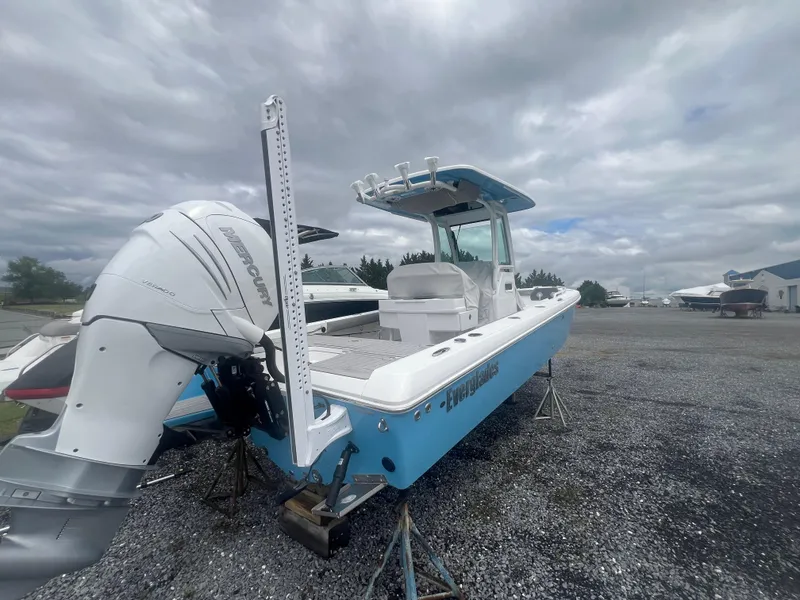 Slide: The Image of 2023 Everglades 253 CC boat with outboard motor on gravel lot under cloudy sky. - 11