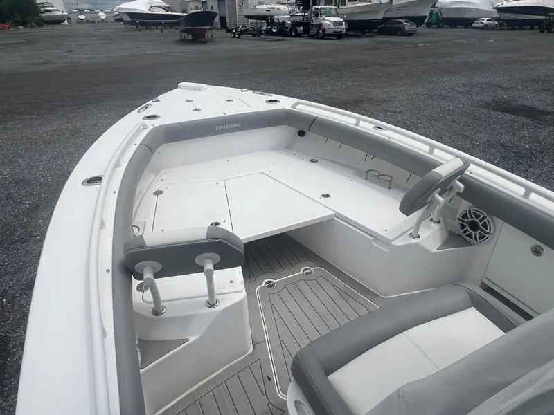 Slide: The Image of 2023 Everglades 253 CC boat interior with seating and steering wheel, docked in a marina. - 13