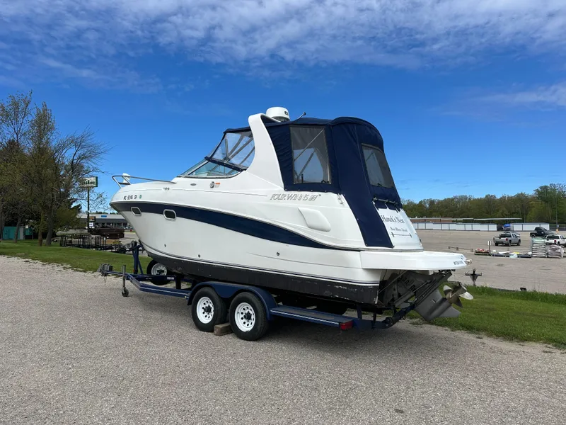 Slide: The Image of 2002 Four Winns 268 Vista boat on trailer, parked outdoors under a clear blue sky. - 2