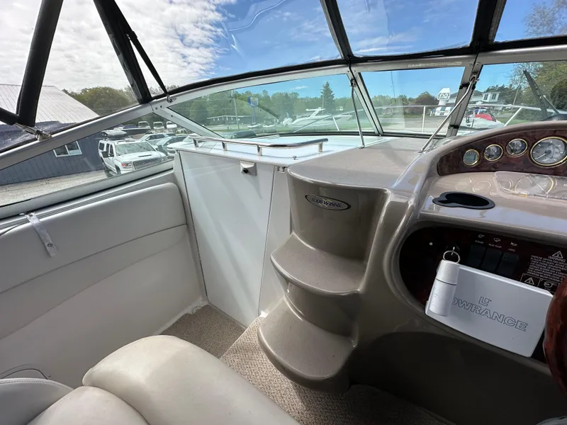 Slide: The Image of 2002 Four Winns 268 Vista boat interior with helm, steps, and dashboard under a clear sky. - 25