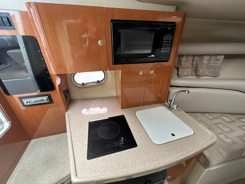 Slide: The Image of 2002 Four Winns 268 Vista boat interior with kitchenette, featuring microwave, sink, and stove. - 28
