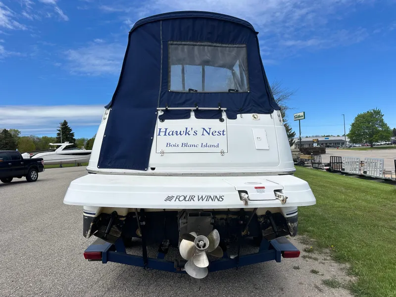 Slide: The Image of 2002 Four Winns 268 Vista boat, rear view, with blue canopy and "Hawk's Nest" signage. - 3