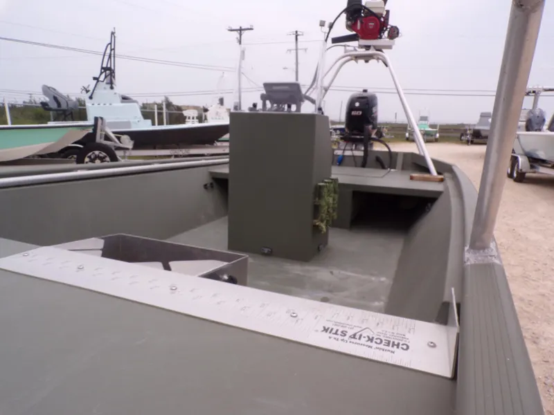 Slide: The Image of 2024 Southfork 1662 EXLSF boat interior with equipment and motor, parked outdoors. - 14