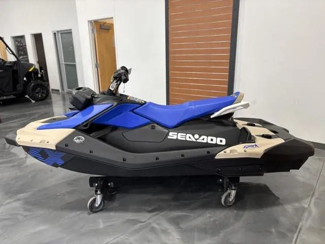 Slide: The Image of 2025 Sea-Doo Spark Trixx Waverunner in showroom, blue and black design, side view. - 5