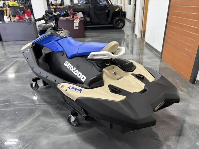 Slide: The Image of 2025 Sea-Doo Spark Trixx Waverunner in showroom, blue and beige design, on display. - 6