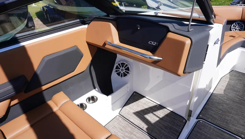 Slide: The Image of 2024 Cobalt CS23 boat interior with brown and black seating, speaker, and cup holders. - 24