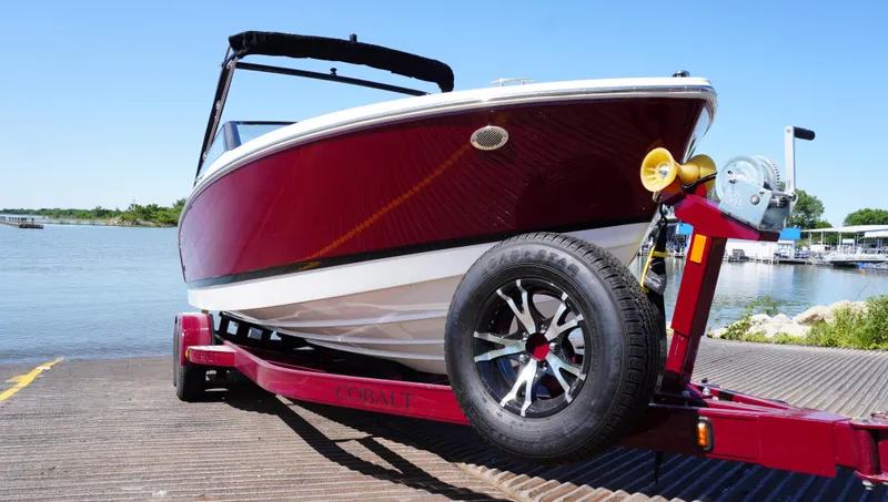 Slide: The Image of 2024 Cobalt CS23 boat on trailer by the water, showcasing sleek design and vibrant red color. - 7