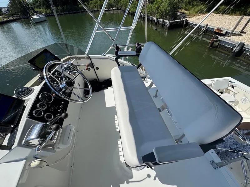 Slide: The Image of 1973 Bertram 28 Sport Fisherman helm with steering wheel and controls, docked by a calm waterway. - 14