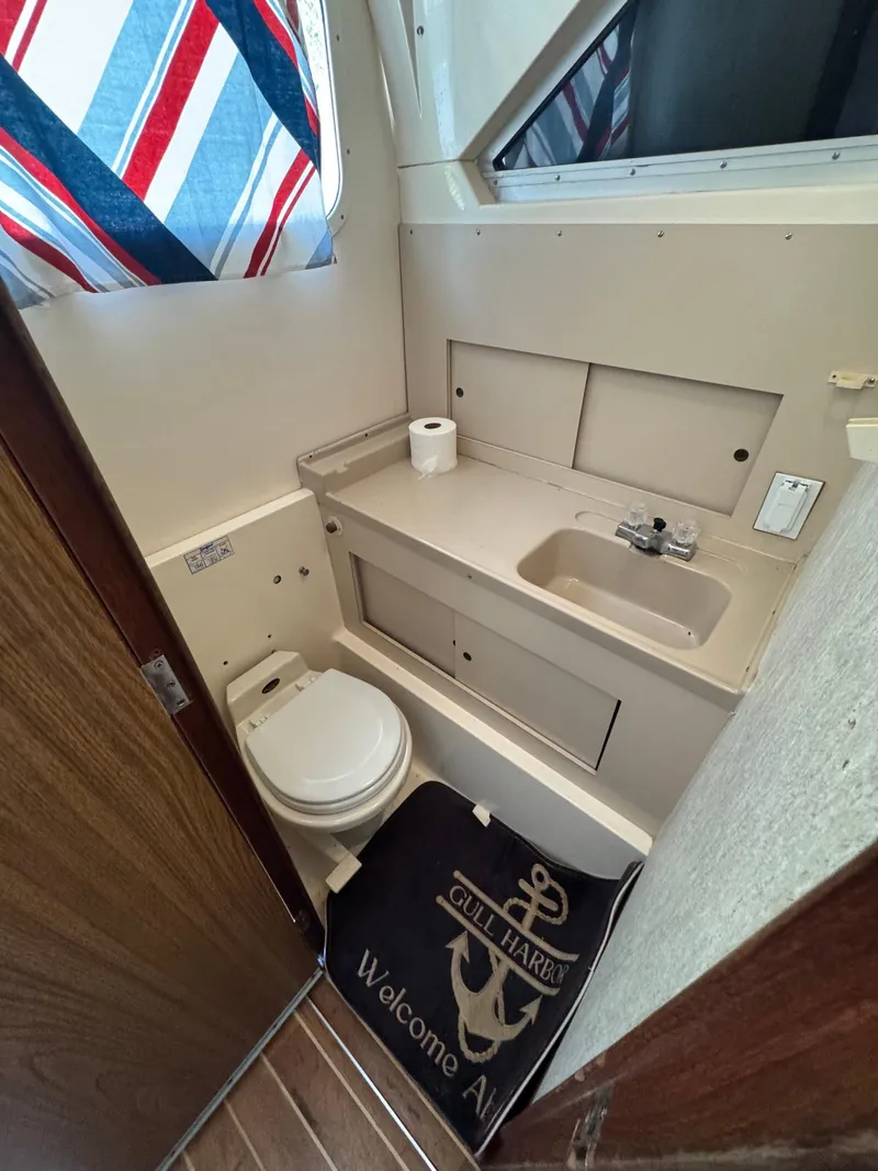 Slide: The Image of 1973 Bertram 28 Sport Fisherman bathroom with sink, toilet, and nautical decor. - 20