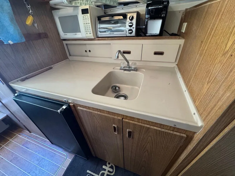 Slide: The Image of 1973 Bertram 28 Sport Fisherman galley with sink, microwave, and wooden cabinetry. - 21