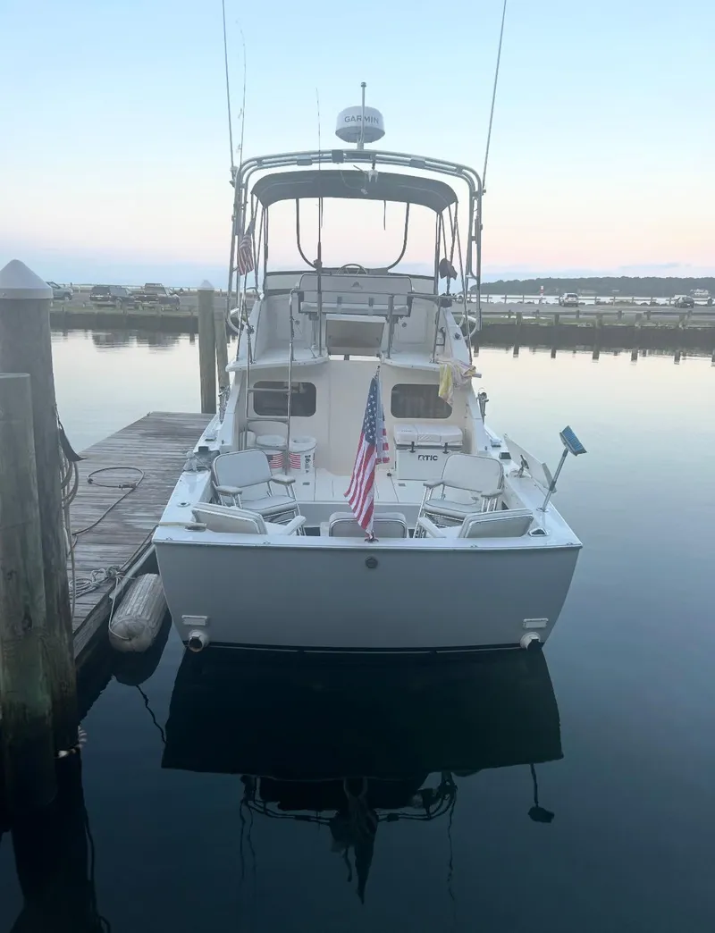 Slide: The Image of 1973 Bertram 28 Sport Fisherman docked at sunset, featuring fishing gear and American flag. - 5