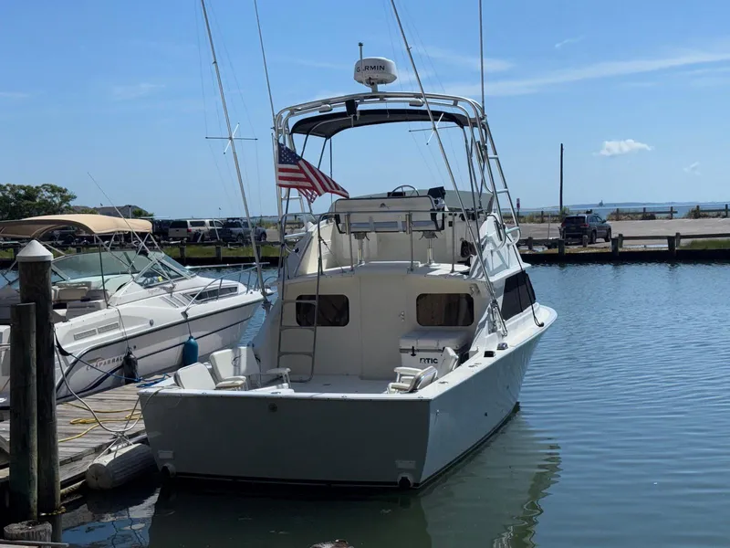 Slide: The Image of 1973 Bertram 28 Sport Fisherman docked at marina, clear sky, American flag displayed. - 7