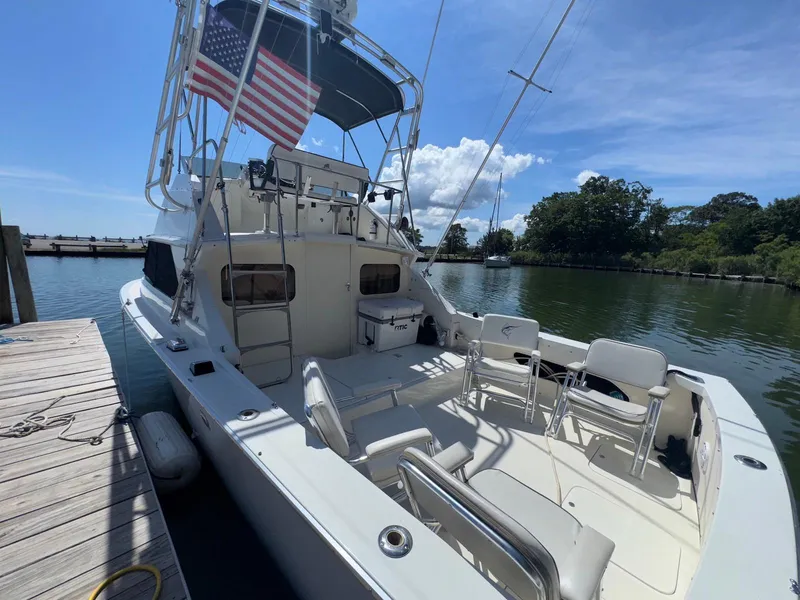 Slide: The Image of 1973 Bertram 28 Sport Fisherman docked, featuring spacious deck and American flag. - 8