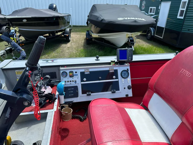 Slide: The Image of 1995 Lund 1660 Pro V Tiller boat interior with red and white seating, control panel, and steering. - 13