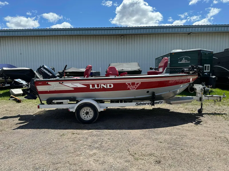 Slide: The Image of 1995 Lund 1660 Pro V Tiller boat on trailer, red and white, parked outdoors. - 2