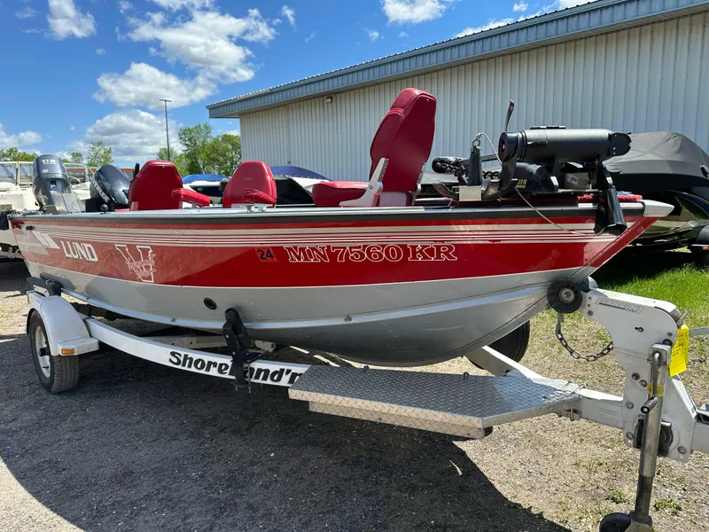 Slide: The Image of 1995 Lund 1660 Pro V Tiller boat on trailer, red and white, parked outdoors. - 3