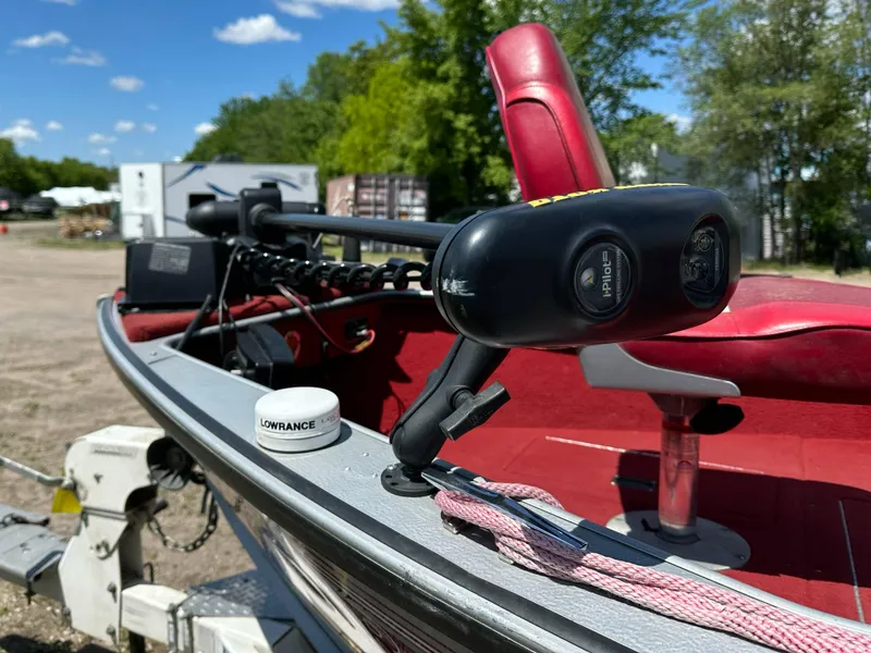 Slide: The Image of 1995 Lund 1660 Pro V Tiller boat with red seating and trolling motor, outdoors. - 6