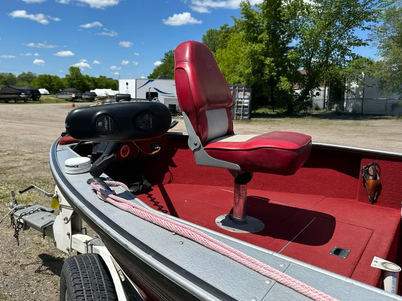Slide: The Image of 1995 Lund 1660 Pro V Tiller boat with red seating, parked outdoors under blue sky. - 7