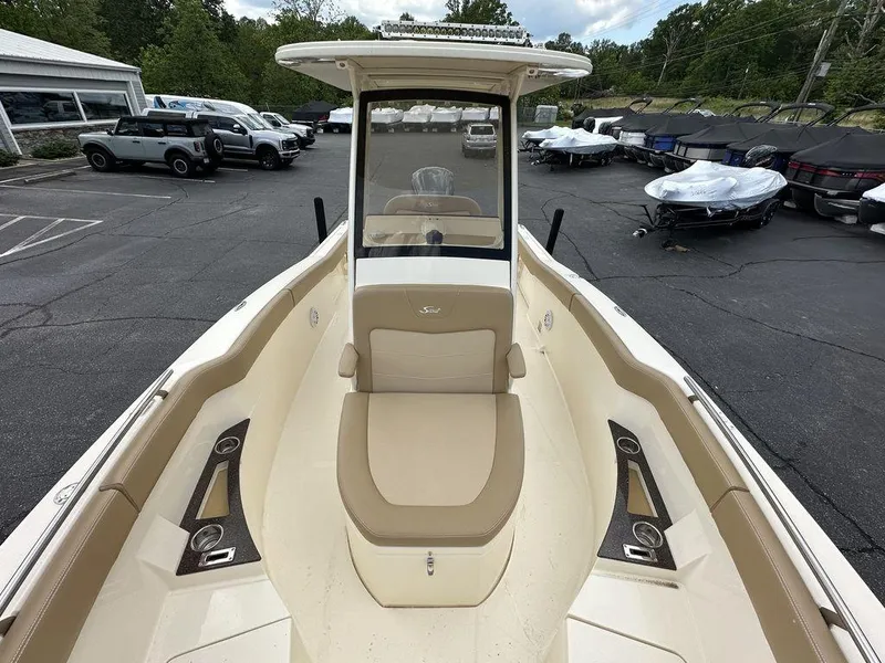 Slide: The Image of 2019 Scout 235 XSF boat with beige seating, parked in a lot with other vehicles. - 12