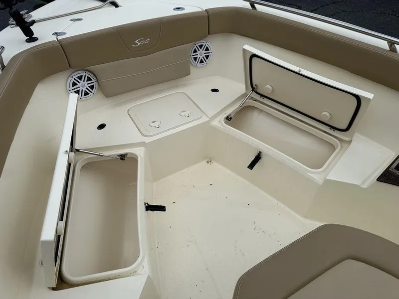 Slide: The Image of 2019 Scout 235 XSF boat interior with open storage compartments and beige seating. - 13