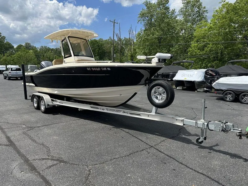 Slide: The Image of 2019 Scout 235 XSF boat on trailer, parked outdoors under a partly cloudy sky. - 4
