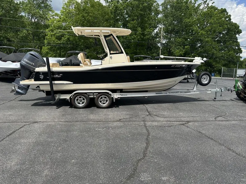 Slide: The Image of 2019 Scout 235 XSF boat on trailer, parked outdoors with trees in background. - 6