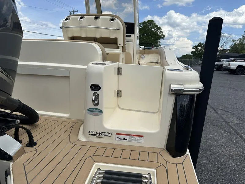 Slide: The Image of 2019 Scout 235 XSF boat with open transom door and teak deck, under a partly cloudy sky. - 7