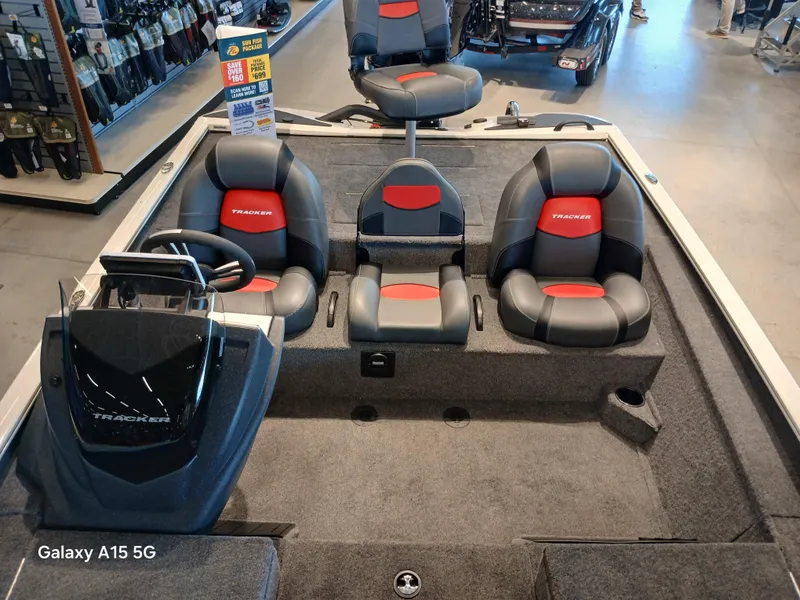 Slide: The Image of 2025 Tracker Savage 215 boat interior with seating and steering console in showroom. - 6