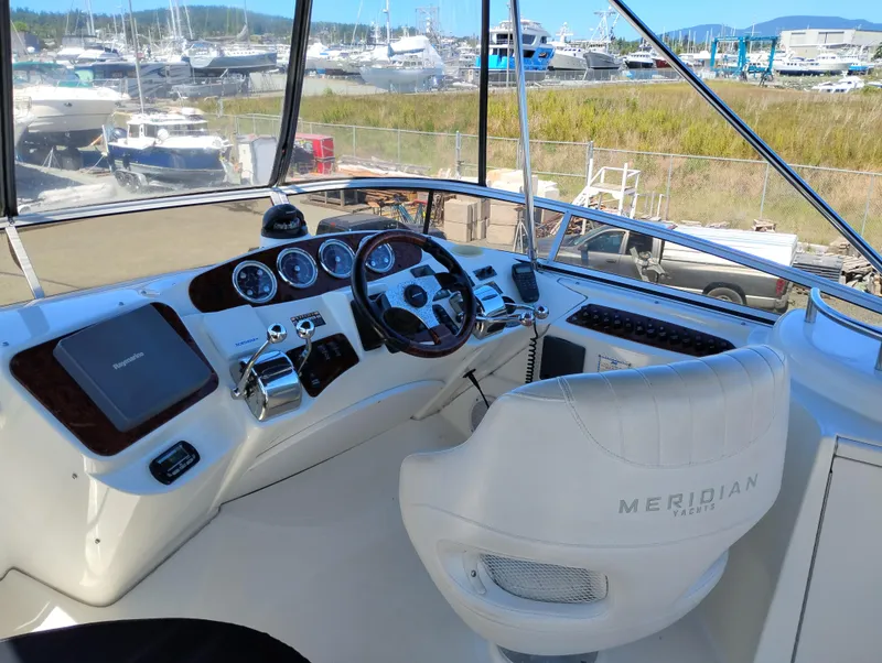 Slide: The Image of 2006 Meridian 341 Sedan helm with steering wheel, controls, and gauges in a marina setting. - 10