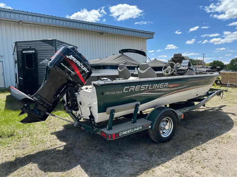 Slide: The Image of 2004 Crestliner 1750 Fish Hawk SC boat with Mercury engine on trailer, outdoors. - 2