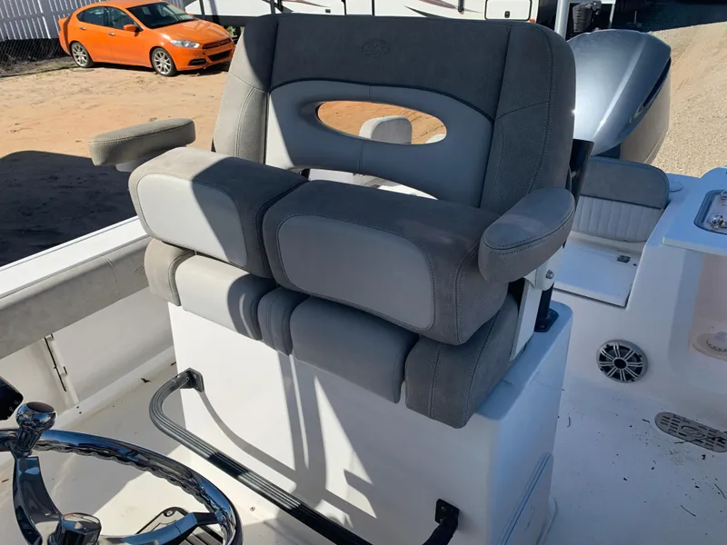 Slide: The Image of 2018 Sea Fox 248 Commander boat seat with steering wheel, parked near an orange car. - 16