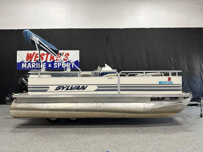 Slide: The Image of 1998 Sylvan Elite 20 pontoon boat displayed indoors with blue canopy. - 0