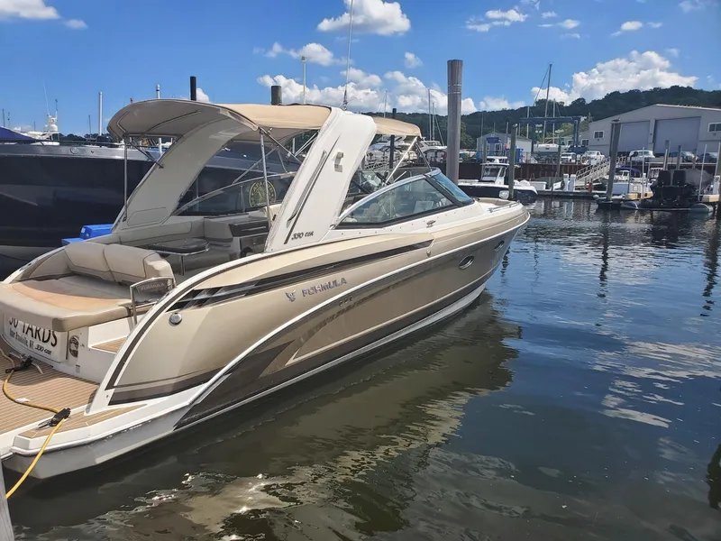 Slide: The Image of 2015 Formula 330 Crossover Bowrider docked at marina under blue sky. - 2