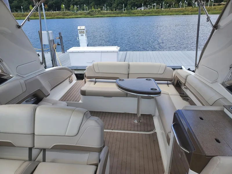 Slide: The Image of 2015 Formula 330 Crossover Bowrider interior with seating and table, docked by a lake. - 9