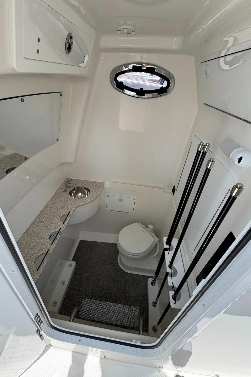 Slide: The Image of 2024 Regulator 31 boat interior with compact bathroom, featuring a toilet, sink, and storage. - 10
