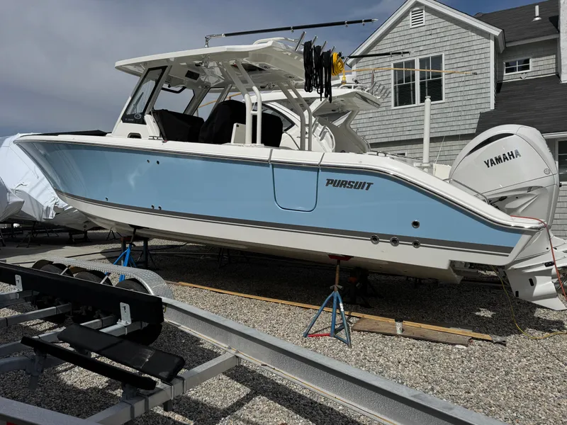 Slide: The Image of 2025 Pursuit S 328 boat with Yamaha engine on display near a house. - 0