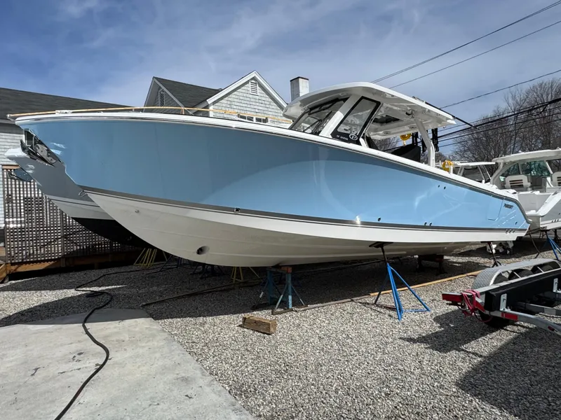 Slide: The Image of 2025 Pursuit S 328 boat in light blue, displayed on gravel with a clear sky backdrop. - 1