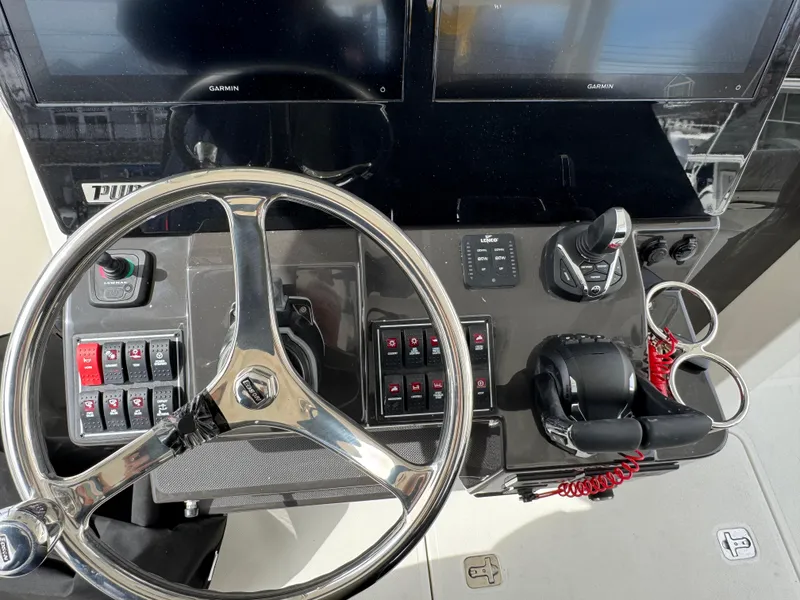 Slide: The Image of Control panel of 2025 Pursuit S 328 boat with steering wheel and navigation screens. - 11