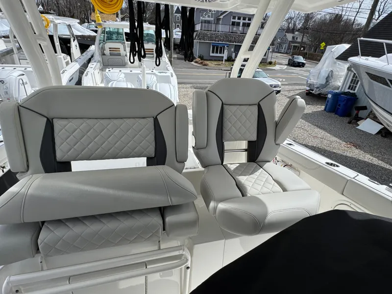 Slide: The Image of 2025 Pursuit S 328 boat seats with quilted gray upholstery, docked in a marina. - 12