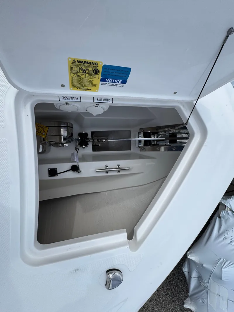 Slide: The Image of 2025 Pursuit S 328 boat storage compartment with safety labels and equipment. - 15