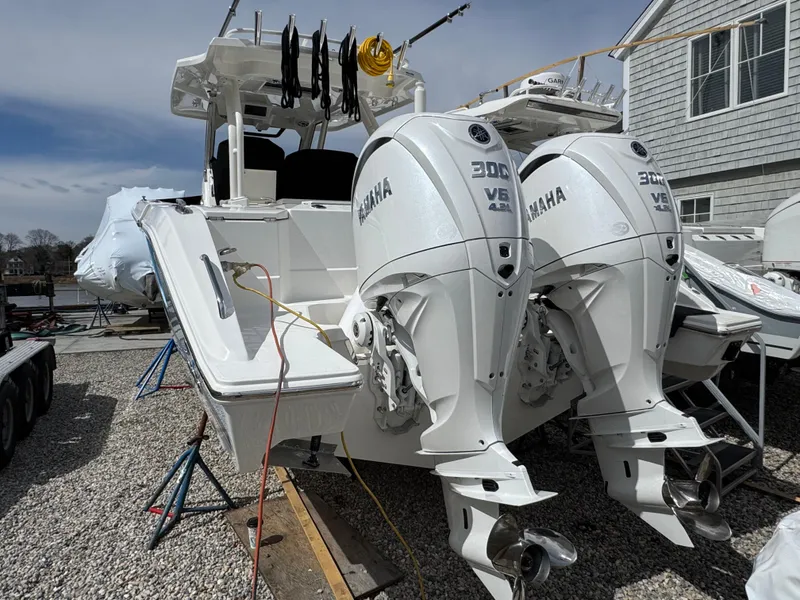 Slide: The Image of 2025 Pursuit S 328 boat with dual Yamaha 300 engines, docked on gravel. - 2